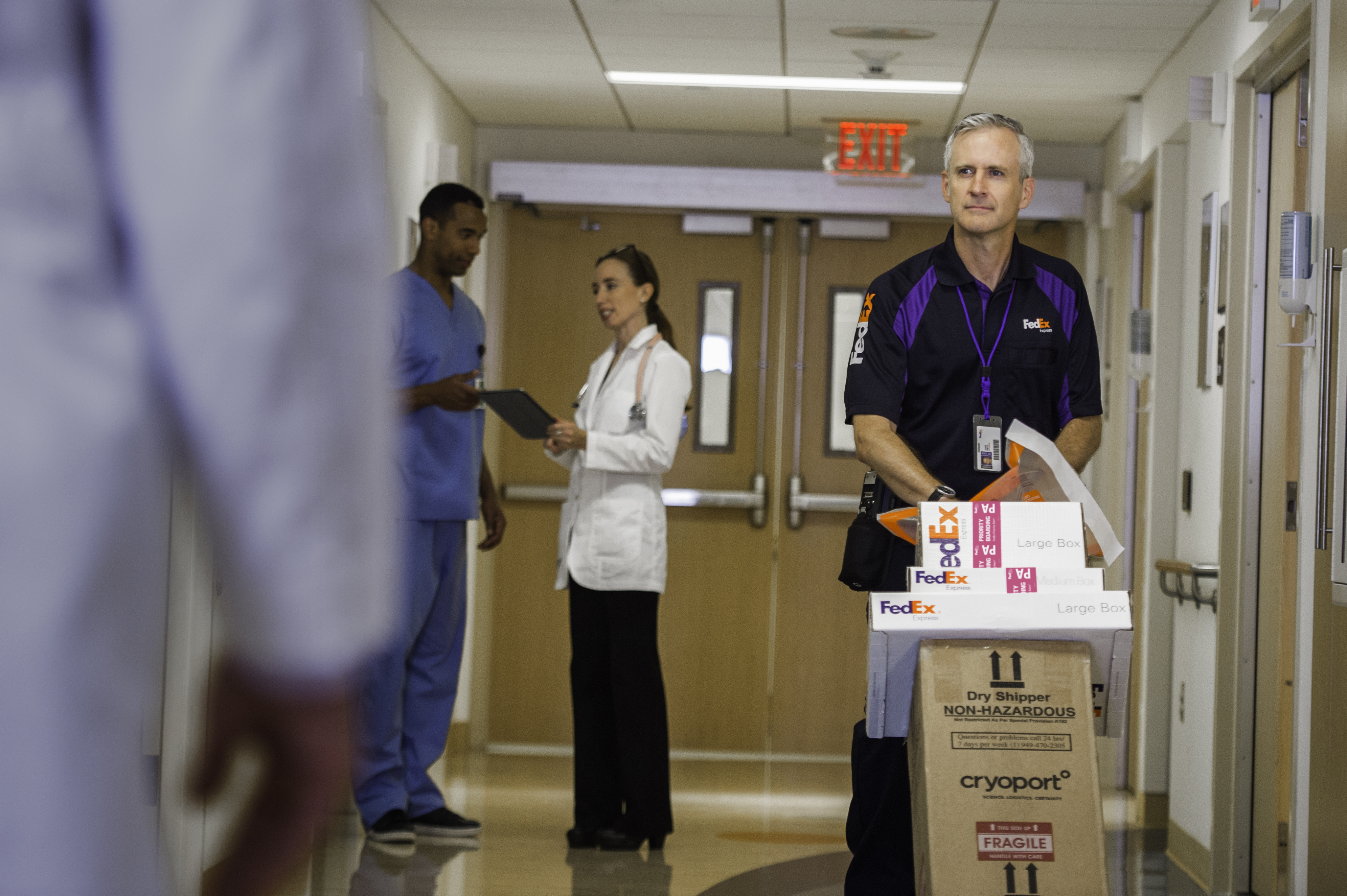 FedEx-kuriiri kävelee käytävää pitkin sairaalassa