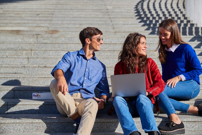 Group of people looking at a laptop on city steps