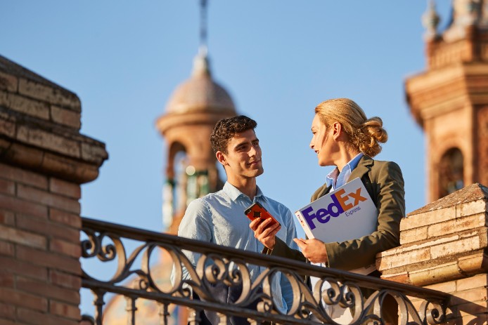 Two people on a bridge talking with a package