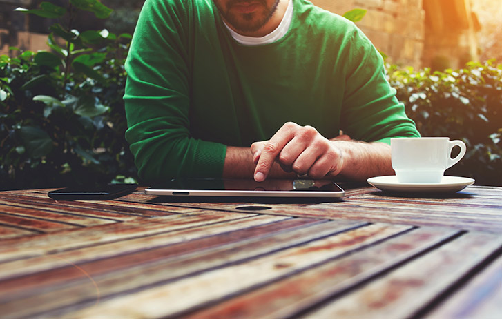 man with coffee on tablet