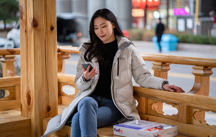 Person sitting crosslegged by windows looking at phone
