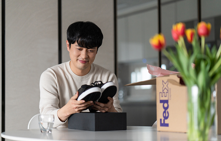 Personne assise regardant des chaussures, à côté d’une boîte FedEx
