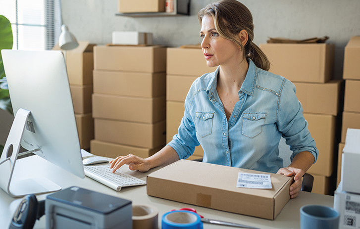 woman with box looking at computer