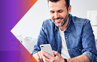 Smiling man looking at his phone while sitting on a couch