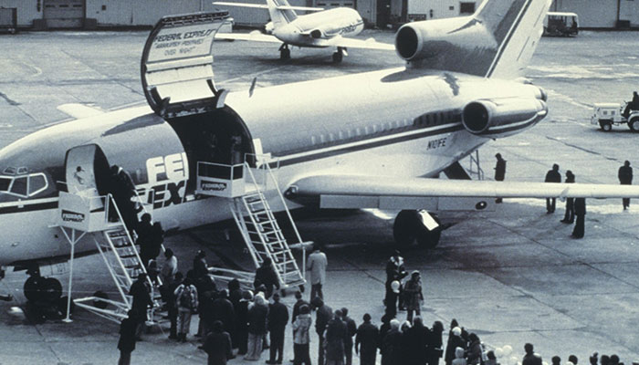 An old picture of a FedEx Jet with it's door open and people gathered around