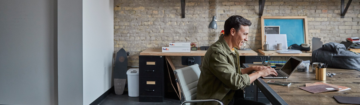 Person at desk typing on laptop and smiling