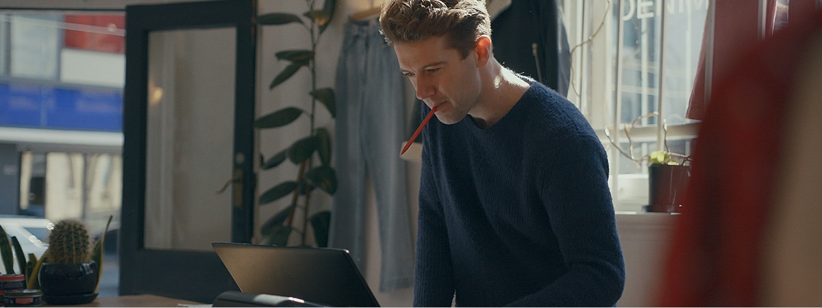 Man looking at cash register screen with a pen in his mouth