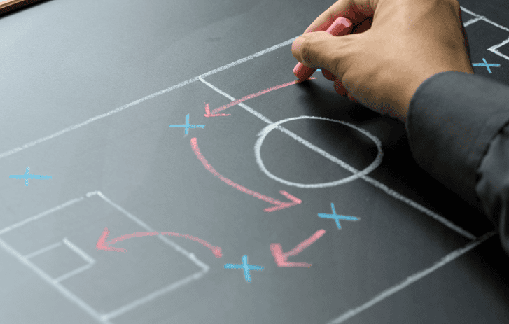 A person draws a strategy on a football field diagram.