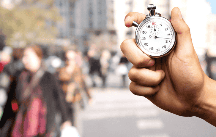 A hand sets a timer against the backdrop of a busy city filled with people.