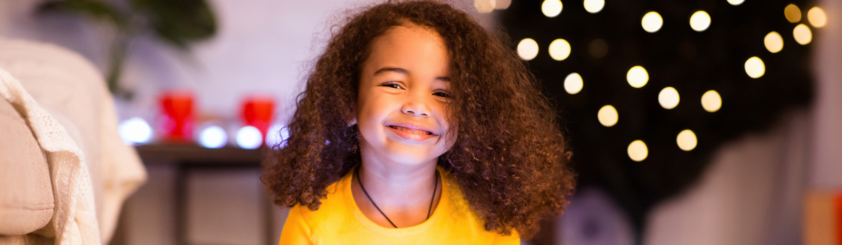 Child opening box in festive holiday room with lights and tree