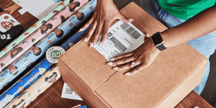 A person places a shipping label on a package. 