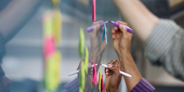 Plusieurs personnes en train d’écrire sur des post-its collés au mur