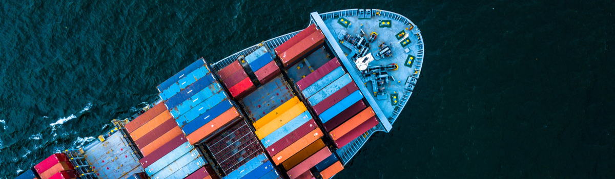Aerial view of a container ship stacked with colorful cargo containers at sea. 