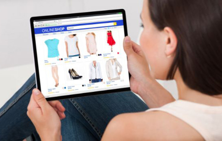 Person browsing an online clothing store on a tablet at home.