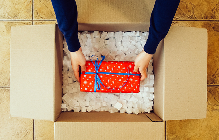 Hands putting a wrapped present in a box
