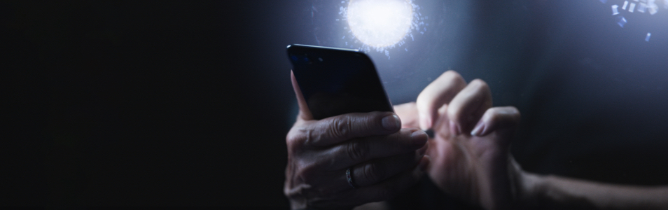 Hands holding a phone with a spotlight on them