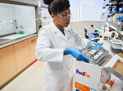 Technician in lab coat fills a FedEx cold box