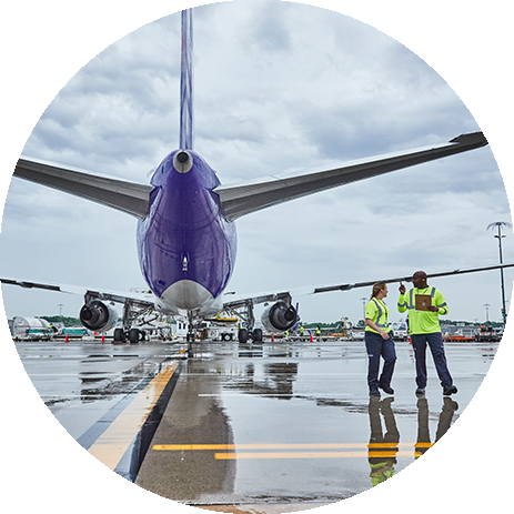 Trabalhadores da FedEx atrás de um avião numa pista