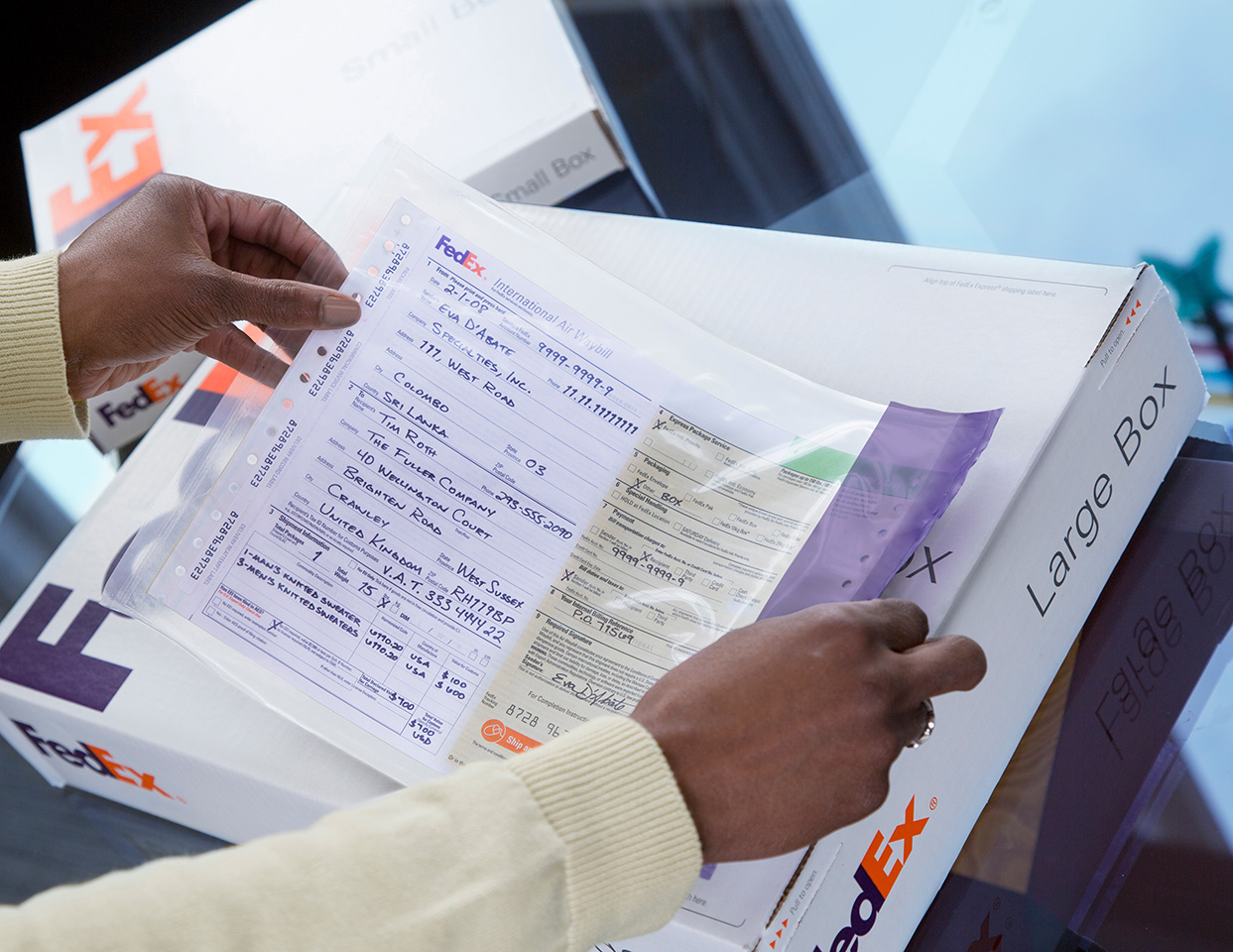 Hands attaching an air waybill to a FedEx box