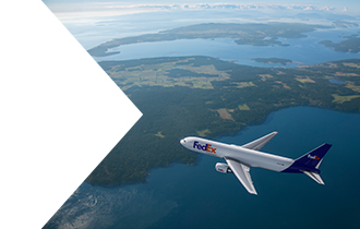 FedEx Plane flying over water with an island in the background