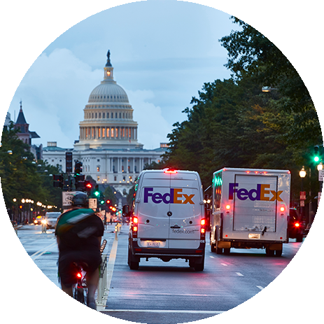Bicyclist, FedEx van and FedEx Truck driving on a road toward the White House of the US