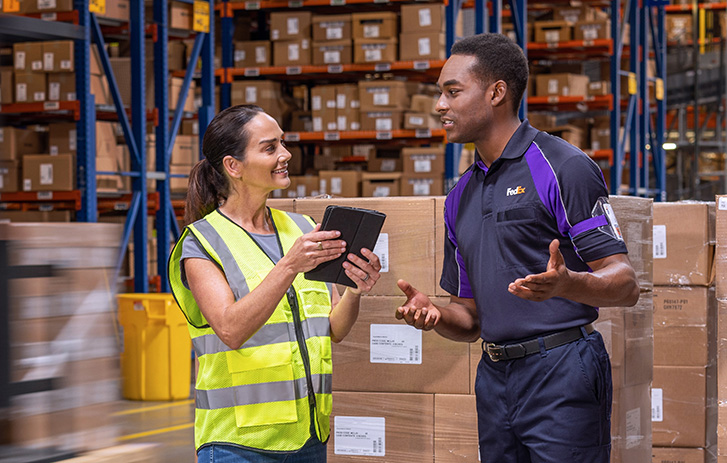 Corriere FedEx che sorride e parla con un lavoratore in un magazzino