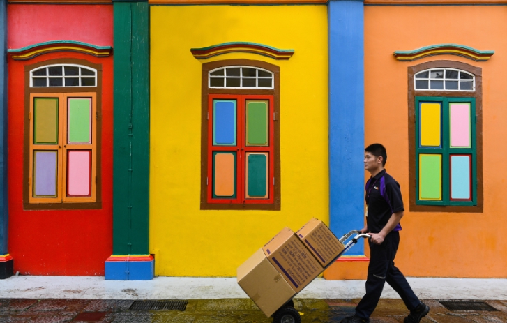 FedEx-Kurier mit Kisten auf einem Warenkorb vor einem bunten Gebäude