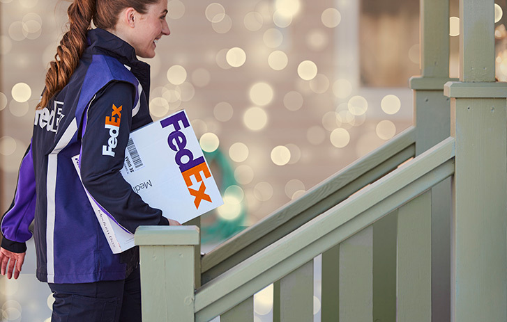 FedEx employee carrying package to front steps