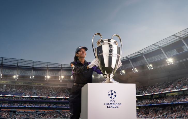 Vrouw op voetbalveld met UEFA-trofee