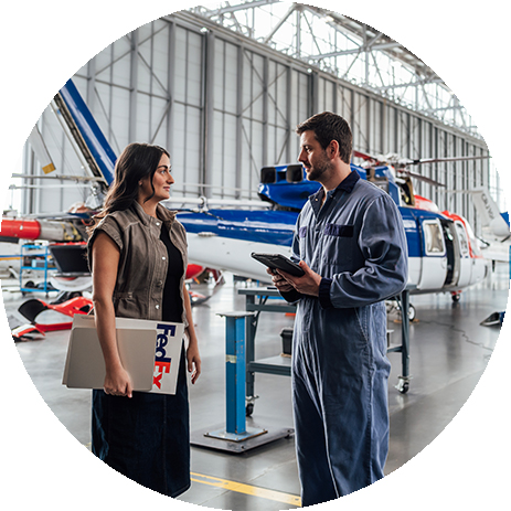 Woman with FedEx package and man standing in front of helicopter