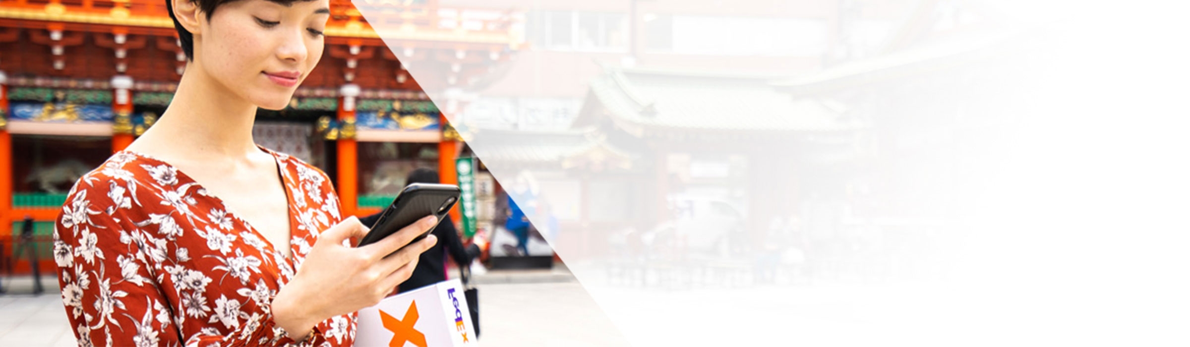 אישה בעלת מראה אסייתי אוחזת בחבילה ומסתכלת על טלפון נייד