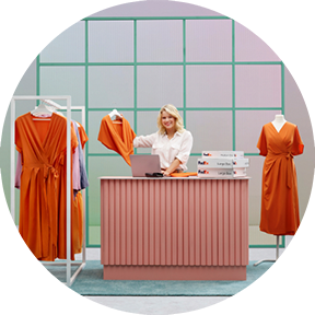Person at a desk with dresses on racks