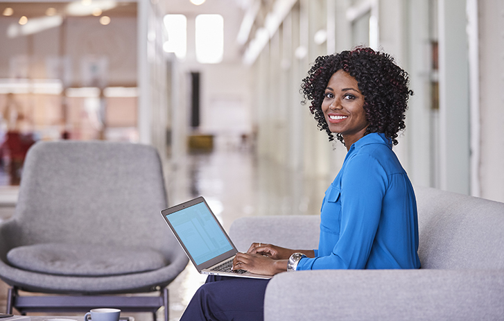 Smiling person at a laptop in an office