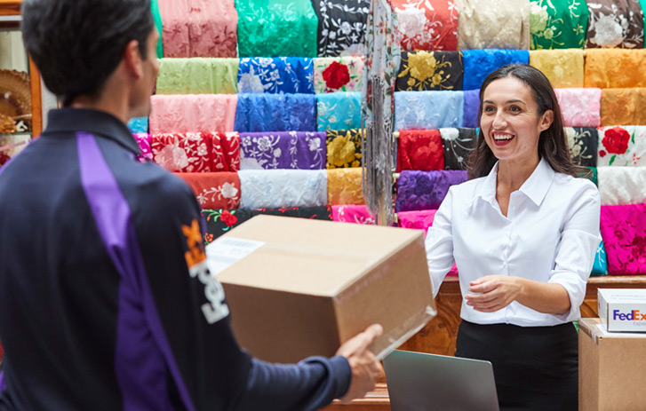 A FedEx courier picks up a package from an Asian clothing store.