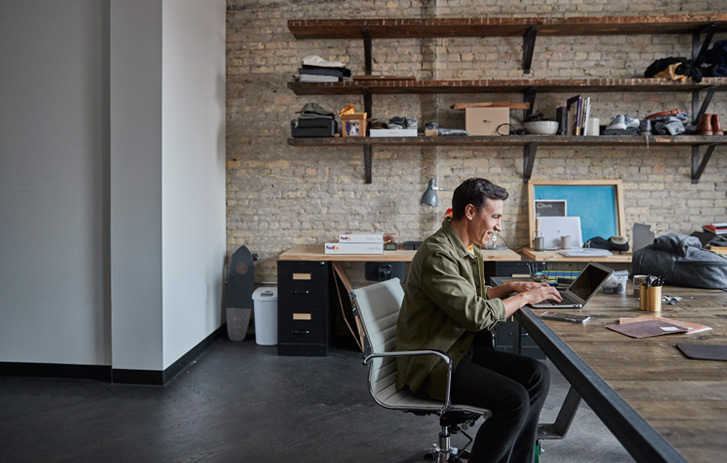A man works on a laptop in his home office.