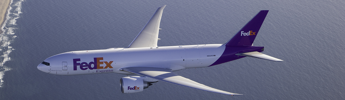 FedEx plane flying over water toward land