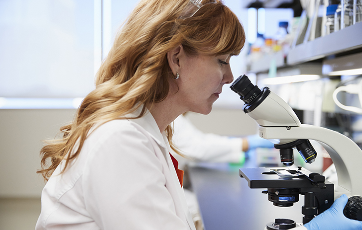 Clinical Research Female Scientist looking into a microscope