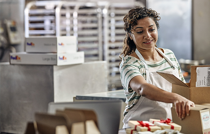 Smiling woman holding two boxes amid sweets