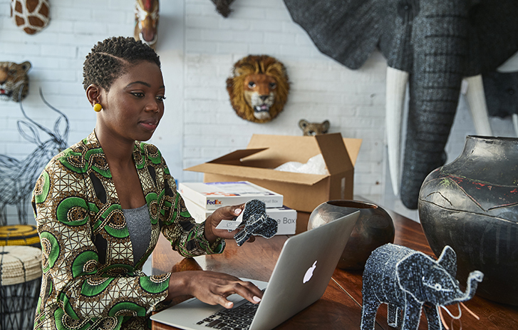 Woman looking at laptop holding a slip of paper in one hand