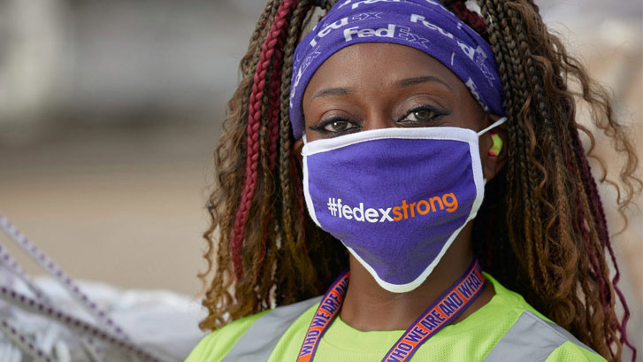 Miembro del equipo de FedEx usando una mascarilla «FedEx Strong»