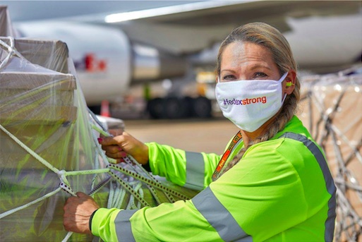 Miembro del equipo de FedEx usando una mascarilla «FedEx Strong» sobre una rampa