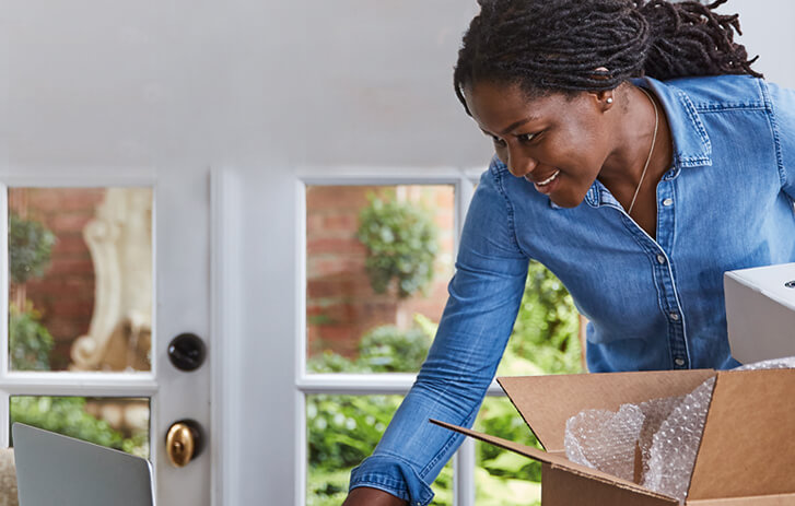 Woman packing a shipment and browsing computer