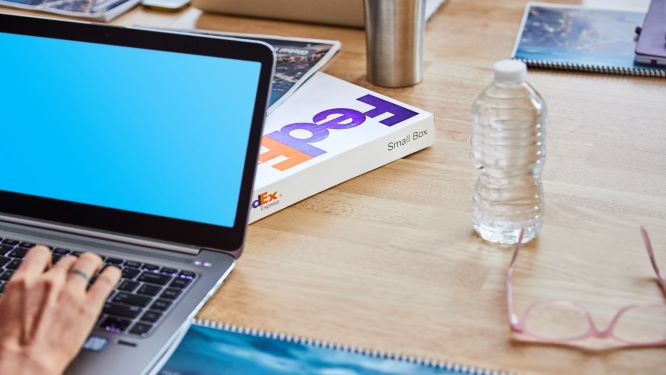 computer resting on a desk next to a FedEx package