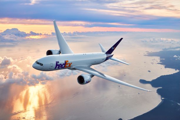 FedEx plane flying above the coast line at sunset