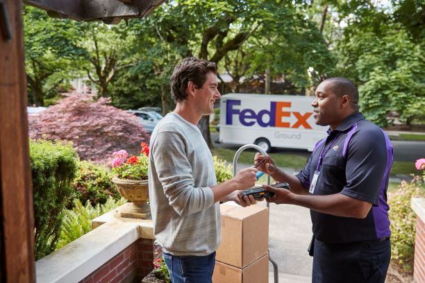 man receiving a package and conversing with a FedEx team member