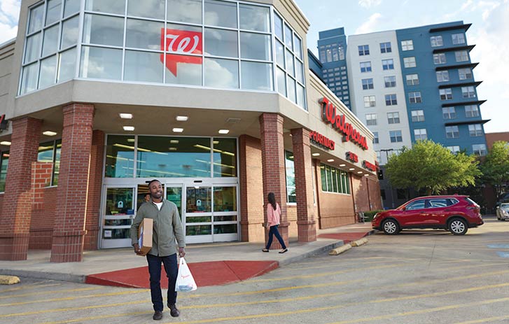 Man walking towards a Walgreens location with a white FedEx box