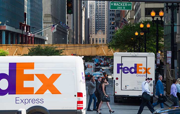 Two FedEx trucks delivering packages