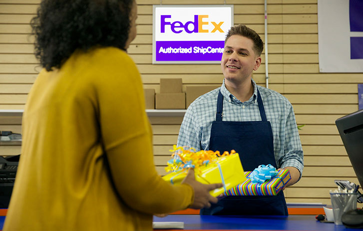 a woman talking to FedEx Authorized ship center employee