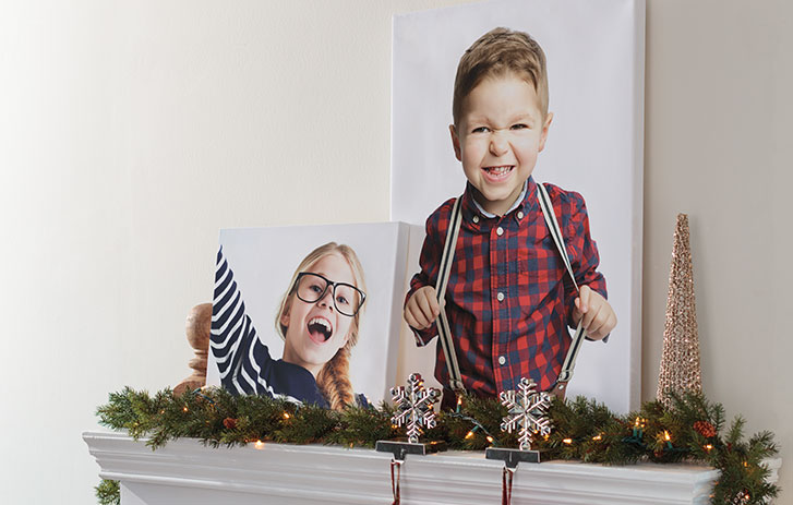 An image of two different sized canvas prints of children on a mantel