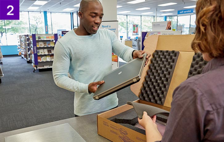 Man dropping off laptop for packaging inside a FedEx Office
